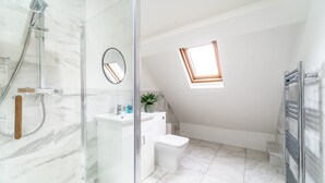 Een moderne badkamer met een douchecabine van glas, een toilet en een klein raam.