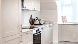 Een moderne keuken met witte kastjes, een ingebouwde oven, een waterkoker en een broodrooster.