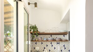 A kitchen with a white countertop, two wooden chairs, a toaster, a kettle, and a laptop. - PRESTIGE SEA VIEW VILLA SCANNELLA (Forio)