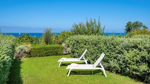 Two white lounge chairs with towels, a well-maintained lawn, and a view of the sea. - PRESTIGE SEA VIEW VILLA SCANNELLA (Forio)