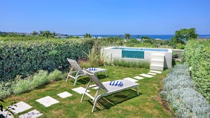 Un espace piscine avec des chaises longues et vue sur la mer.