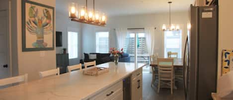 A modern kitchen with a marble countertop, built-in appliances, and pendant lighting.