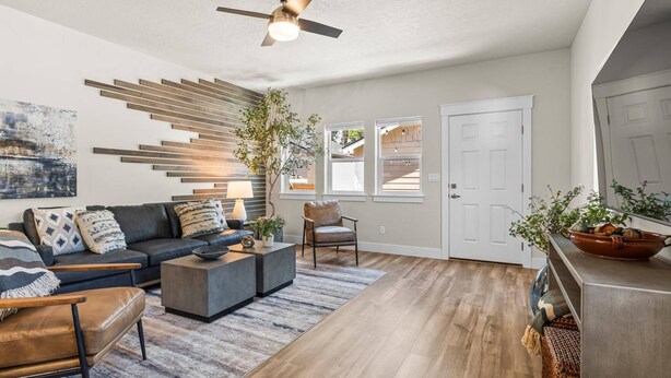 A modern living room with a sofa, coffee table, and chairs, a wooden floor, and a ceiling fan. - Brand New Dog-Friendly Getaway! Perfectly Positioned for Boise Adventures! Walk to Grocery & More! (Boise)