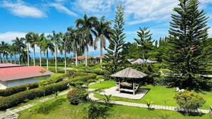A lush garden with a gazebo, palm trees, and a view of the ocean. - Tugsaw Resort (El Salvador)