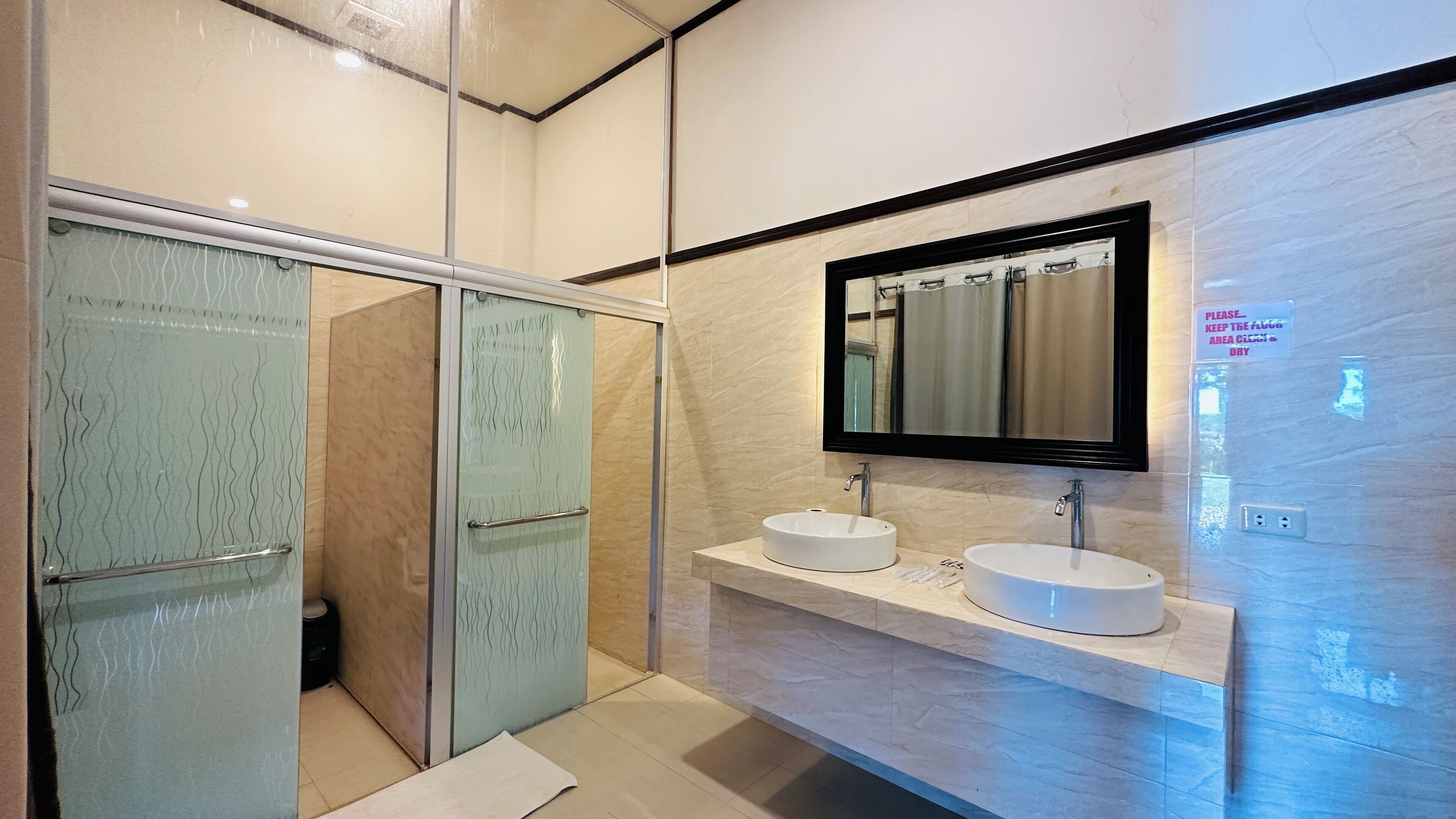A modern bathroom with a glass shower enclosure, two sinks, and a large mirror.