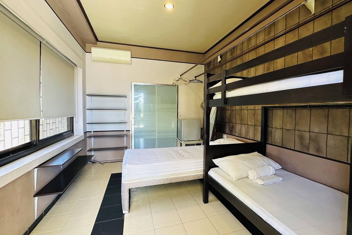 A bunk bed room with a window, a mirror, and a small table.