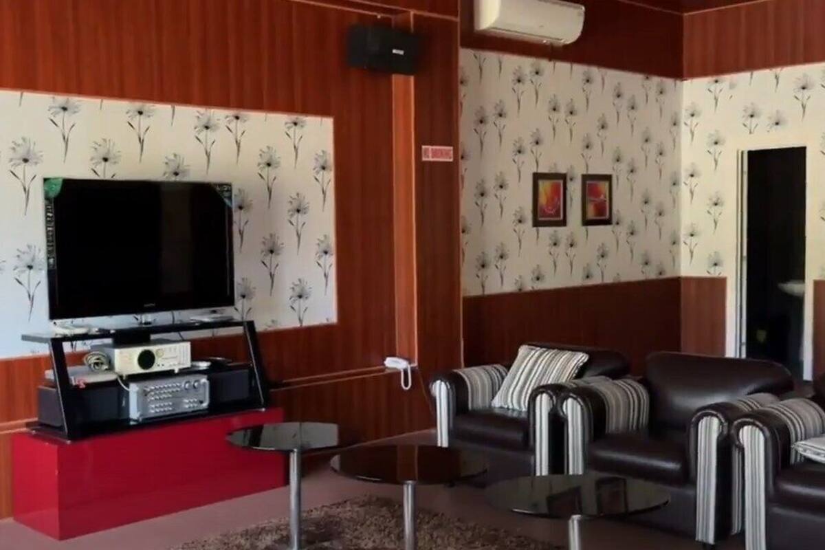 A modern living room with a flat-screen TV, leather sofa, and a red accent wall.