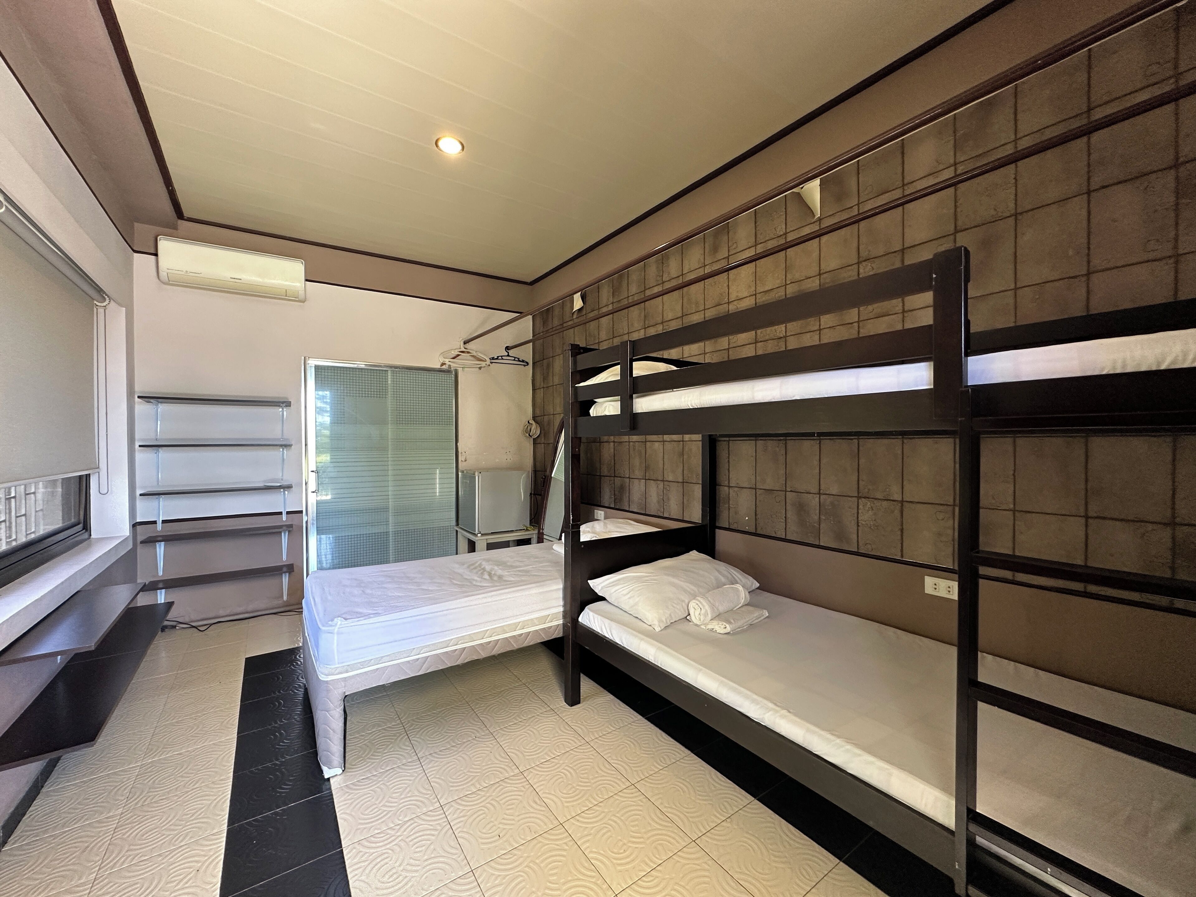 A bunk bed room with a shower, a small table, and a window.
