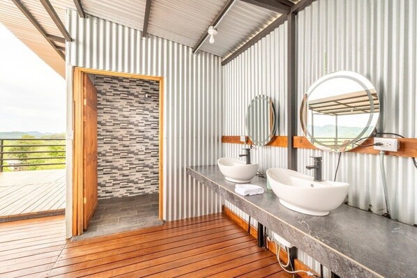 A modern bathroom with two sinks, a large mirror, and a view of the outdoors.