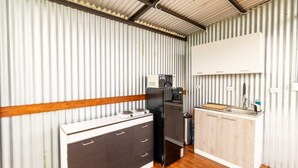 Eine kleine Küche mit Holzausstattung, einem schwarzen Kühlschrank und einem weißen Spülbecken.