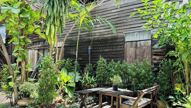 Ein rustikales Holzgebäude mit Garten, der Kübelpflanzen und einem Holztisch zeigt.