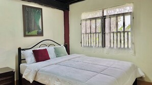 Ein Schlafzimmer mit einem Bett, einem Nachttisch, einem Gemälde und einem Fenster mit Vorhängen.
