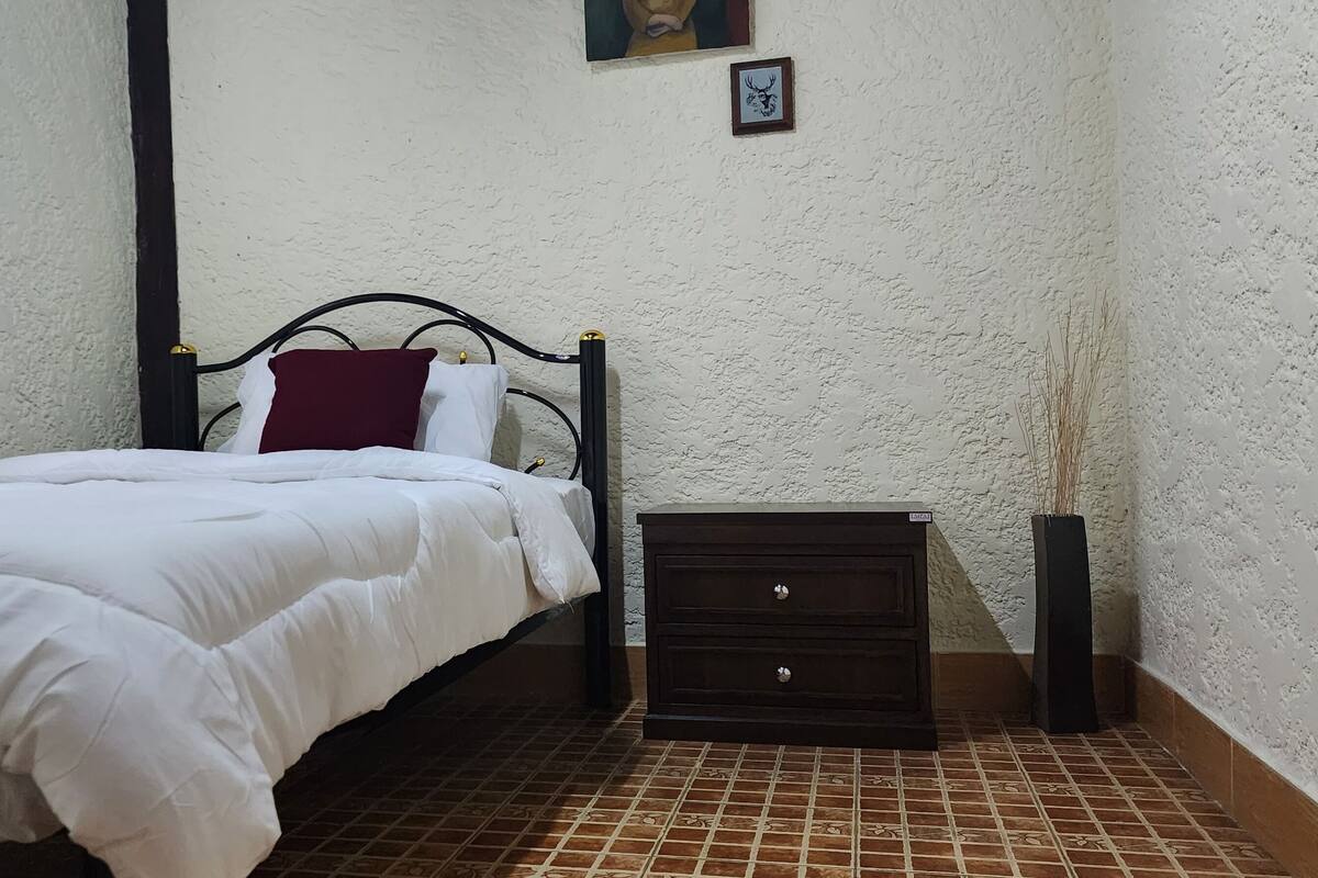 Une chambre à coucher avec un lit, une table de chevet et une étagère fixée au mur.