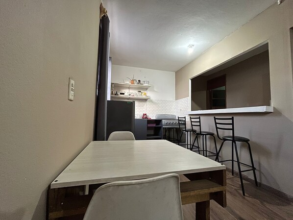 Una cocina compacta con comedor, que incluye una mesa y sillas de madera, un refrigerador y una estufa.