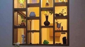Une étagère murale dotée de plusieurs compartiments, chacun contenant divers objets décoratifs et plantes.