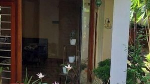 Un espace patio agrémenté de plantes en pot, une porte vitrée donnant sur un espace intérieur et une structure en bois.