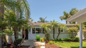 A single-story house with a covered porch, palm trees, and a small garden. - Leucadia "Ponto" Bungalow ~ walk everywhere with beach gear! (Encinitas)