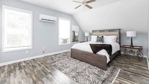 Quarto com uma cama grande, duas mesas de cabeceira com luminárias, um ventilador de teto e um tapete estampado.