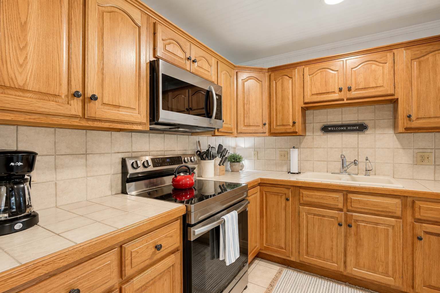 A kitchen with wooden cabinets, a stainless steel stove, a microwave, and a coffee maker.