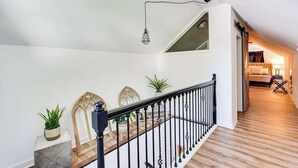 A staircase with a black railing, potted plants, and a hanging light fixture. - The Germantown Gem | 4BR | Ideal Location | Patio (Louisville)