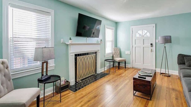 A living room with a fireplace, a television mounted above it, and a sofa. - The Germantown Gem | 4BR | Ideal Location | Patio (Louisville)