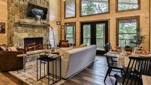 Ein gemütliches Blockhaus-Interieur mit Kamin, Holzwänden, einer Couch und einem Essbereich.