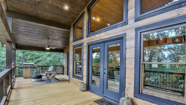 Eine überdachte Terrasse mit Deckenventilator, Grill und Sitzgelegenheit.