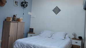 A bedroom with a bed, wooden wardrobe, nightstands, and a ceiling light fixture. - Pavillon Pour 4 Personnes au Bord de L'eau (Leucate)