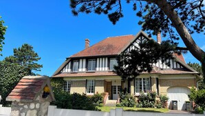A traditional Tudor-style house with a steeply pitched roof, brick facade, and a stone chimney. - Villa spacieuse à Dieppe, 3 chambres, 3 salle de bains, jardin fleuri (Dieppe)