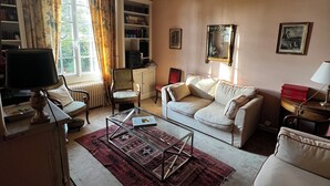 A living room with a sofa, armchairs, a coffee table, a bookshelf, and a television. - Villa spacieuse à Dieppe, 3 chambres, 3 salle de bains, jardin fleuri (Dieppe)