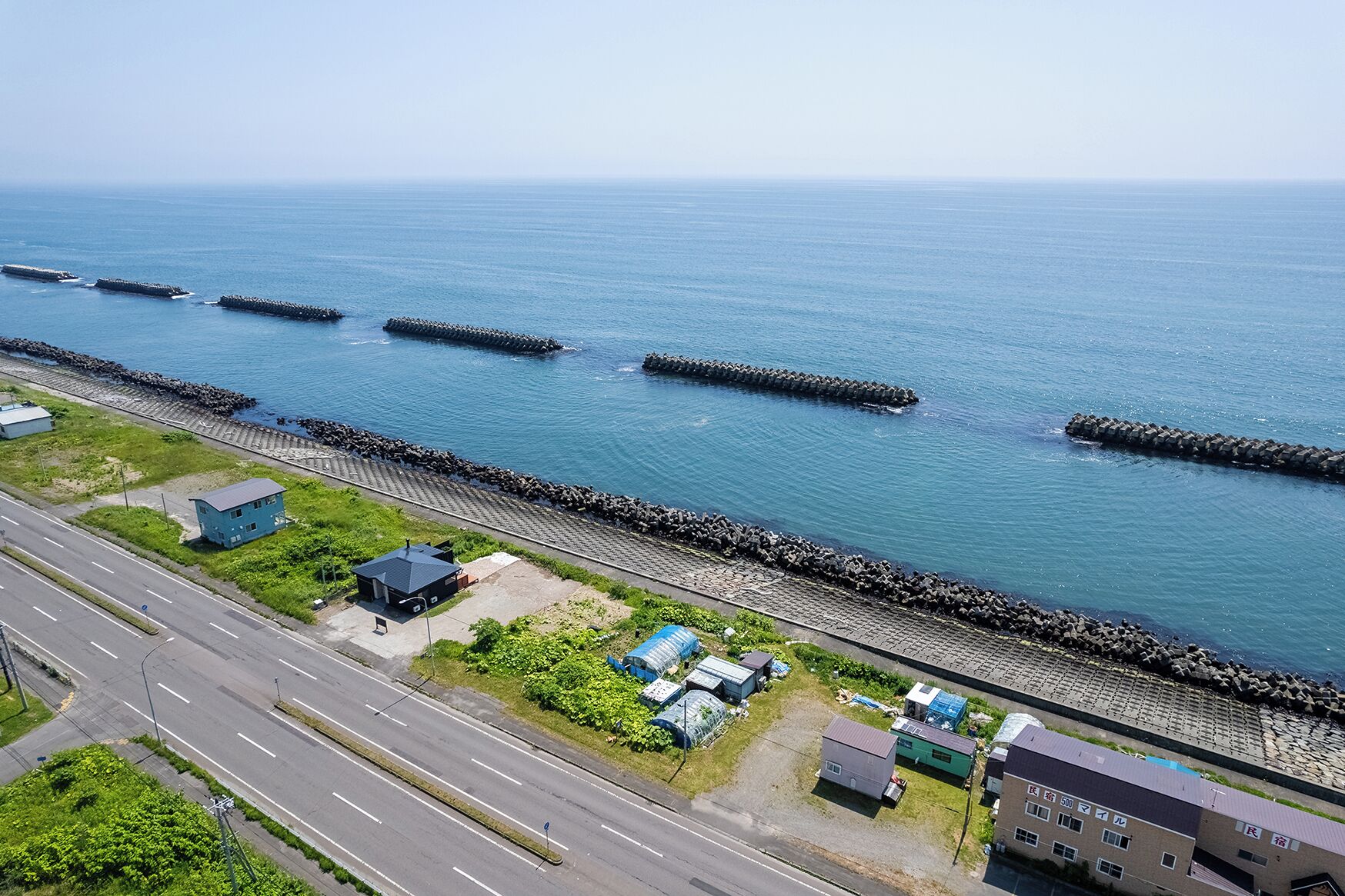A coastal road with a breakwater, a highway, and residential buildings.