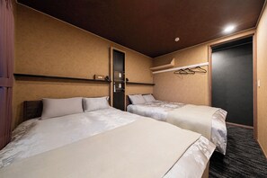 Ein Hotelzimmer mit zwei Betten, einer Tür, einem Kleiderhaken und einem Spiegel an einem Regal.