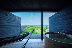 Una cabaña de madera con una bañera de madera y una hamaca.