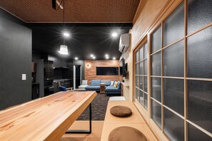 Una sala de estar moderna con una mesa de comedor de madera, un sofá y un amplio ventanal con vidrio esmerilado.