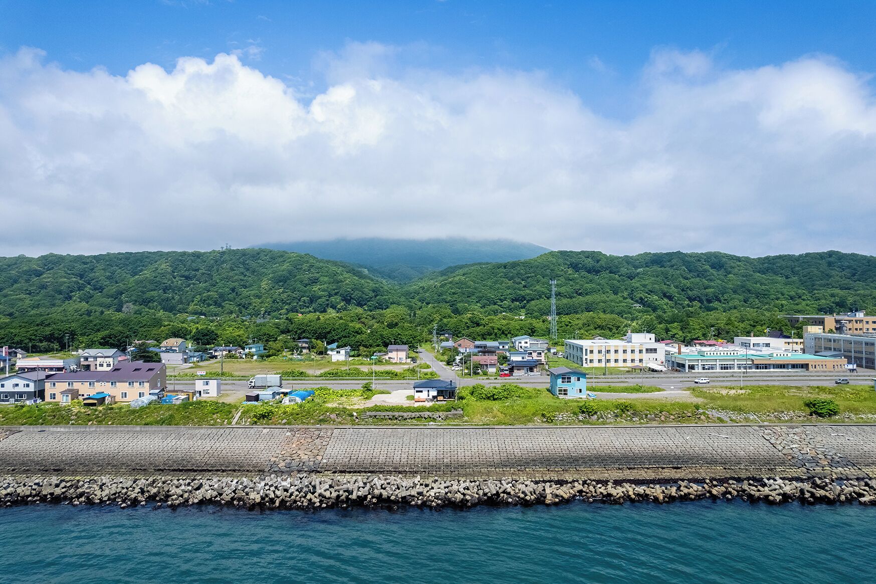 A coastal town with buildings, a dock, and mountains in the background.