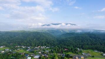 A rural landscape with a small village, houses, and a mountain range in the background.