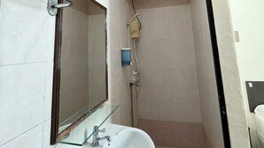 Un baño con lavamanos blanco, un espejo, toallero y zona de ducha.