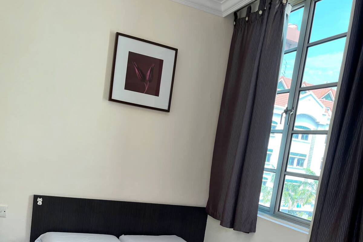 A hotel room with a bed, a framed picture on the wall, and a window with curtains.