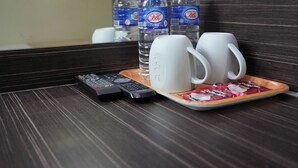 Una bandeja con dos tazas blancas, dos botellas de agua y un control remoto sobre una superficie de madera.
