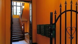 Ein Korridor mit Schachbrettfußboden, einer Treppe und einem schwarzen Eisengitter.