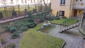 Ein Innenhof mit einer kleinen Sitzecke, einer Treppe und einem Zaun.