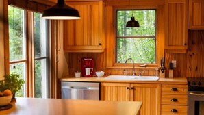 Una cocina con armarios de madera, un lavamanos, una cafetera y un lavavajillas.