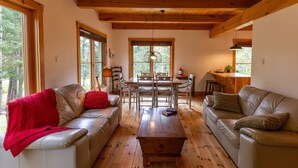 Una sala de estar acogedora con dos sofás de cuero, una mesa de centro de madera y un comedor con mesa y sillas de madera.