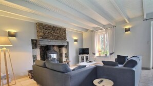 Un salon avec une cheminée en pierre, un canapé, un téléviseur et une lampe.