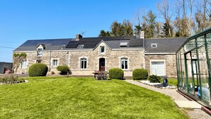 Un bâtiment en pierre doté d’un toit en pente, de panneaux solaires et d’une véranda en verre.
