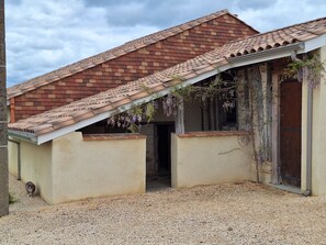 Un bâtiment doté d’un toit en pente, d’une porte et d’un sol recouvert de gravier.