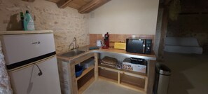 Uma cozinha compacta com geladeira, pia, micro-ondas e prateleiras de madeira.