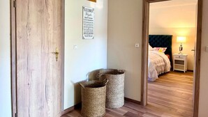 A hallway with a wooden door, a sign with German text, and two woven baskets.