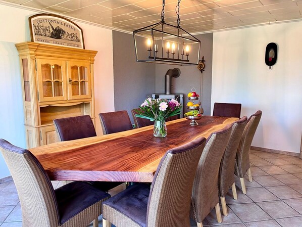 A dining area with a wooden table, wicker chairs, a chandelier, and a cabinet with a sign. - Vacation home Caroline (Hallschlag)
