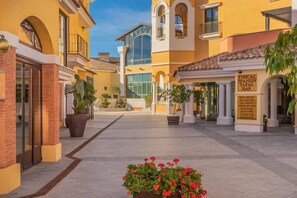 A hotel courtyard with a central open space, potted plants, and a sign for a typical Spanish tapas bar. - Pool views apartment - AO112LT (La Torre Golf Resort)